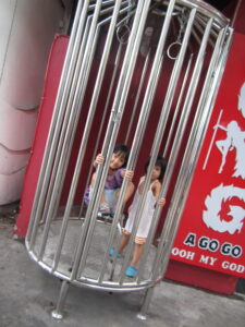 Photo taken on Bangla road in Phuket Thailand. Kids playing in strippers cage. 
